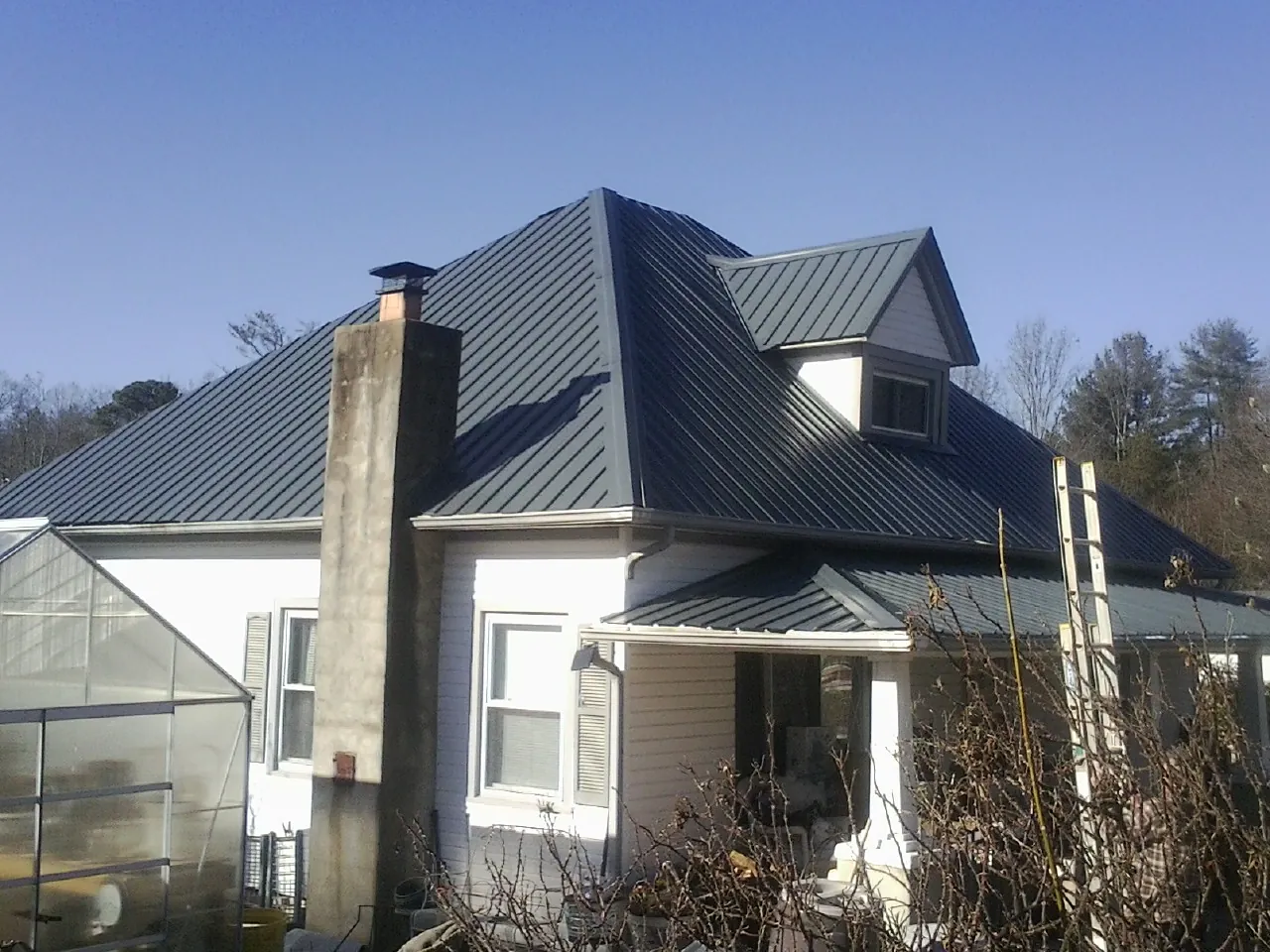 Dark blue standing seam metal roof on a white farmhouse with dormer — Slate & Tile Roof Repair by Roofing Brothers in Mickleton