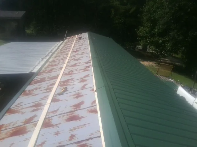 Old rusted panels beside newly installed green metal roofing — Wind Damage Roof Repair by Roofing Brothers in Mickleton
