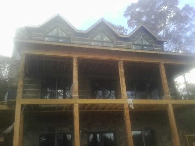 Dormers and porch framing on a large log home under construction — Roof Coating work by our crew in Mickleton