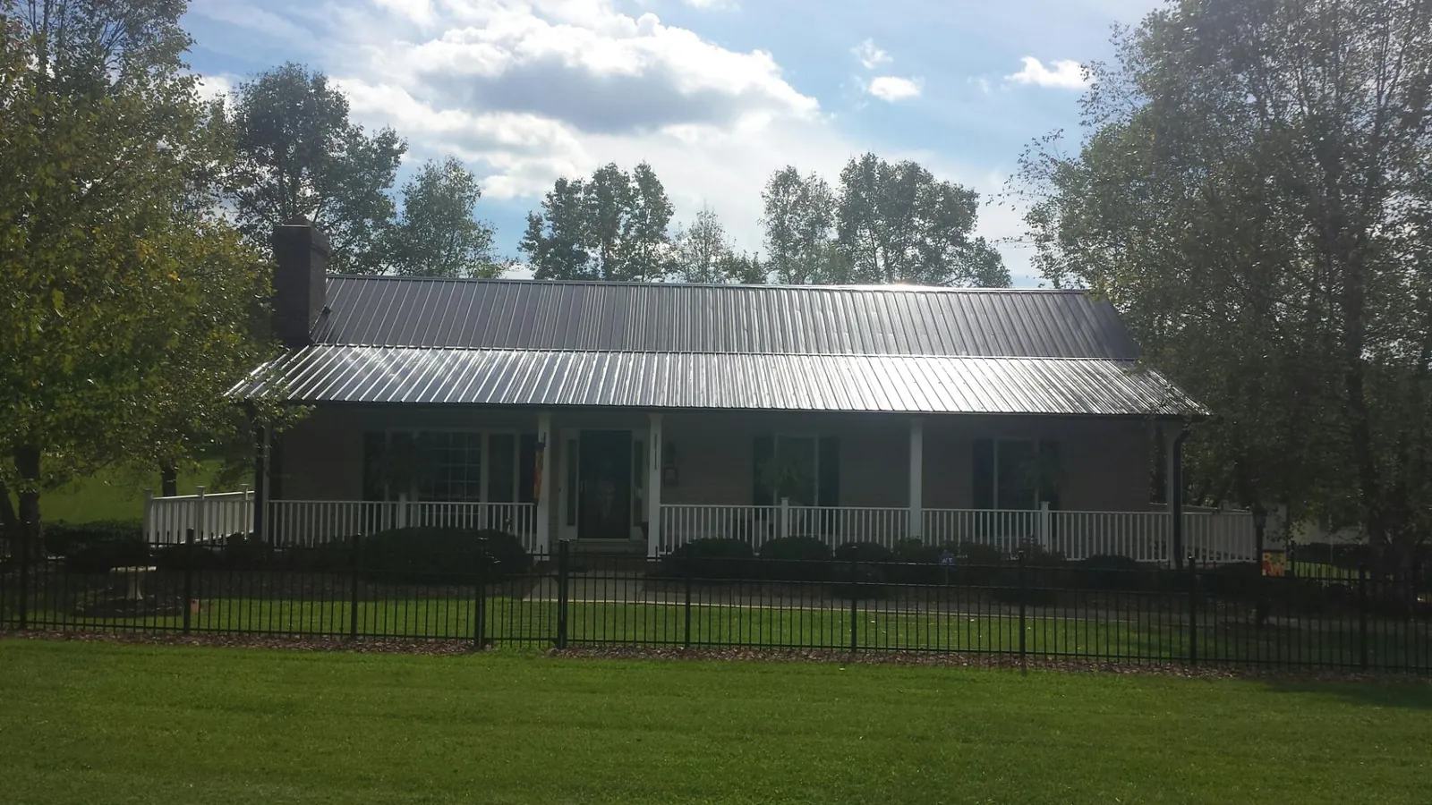 Gray metal roof on a brick ranch with a full width front porch — Gutter Guard Installation work by our crew in Mickleton