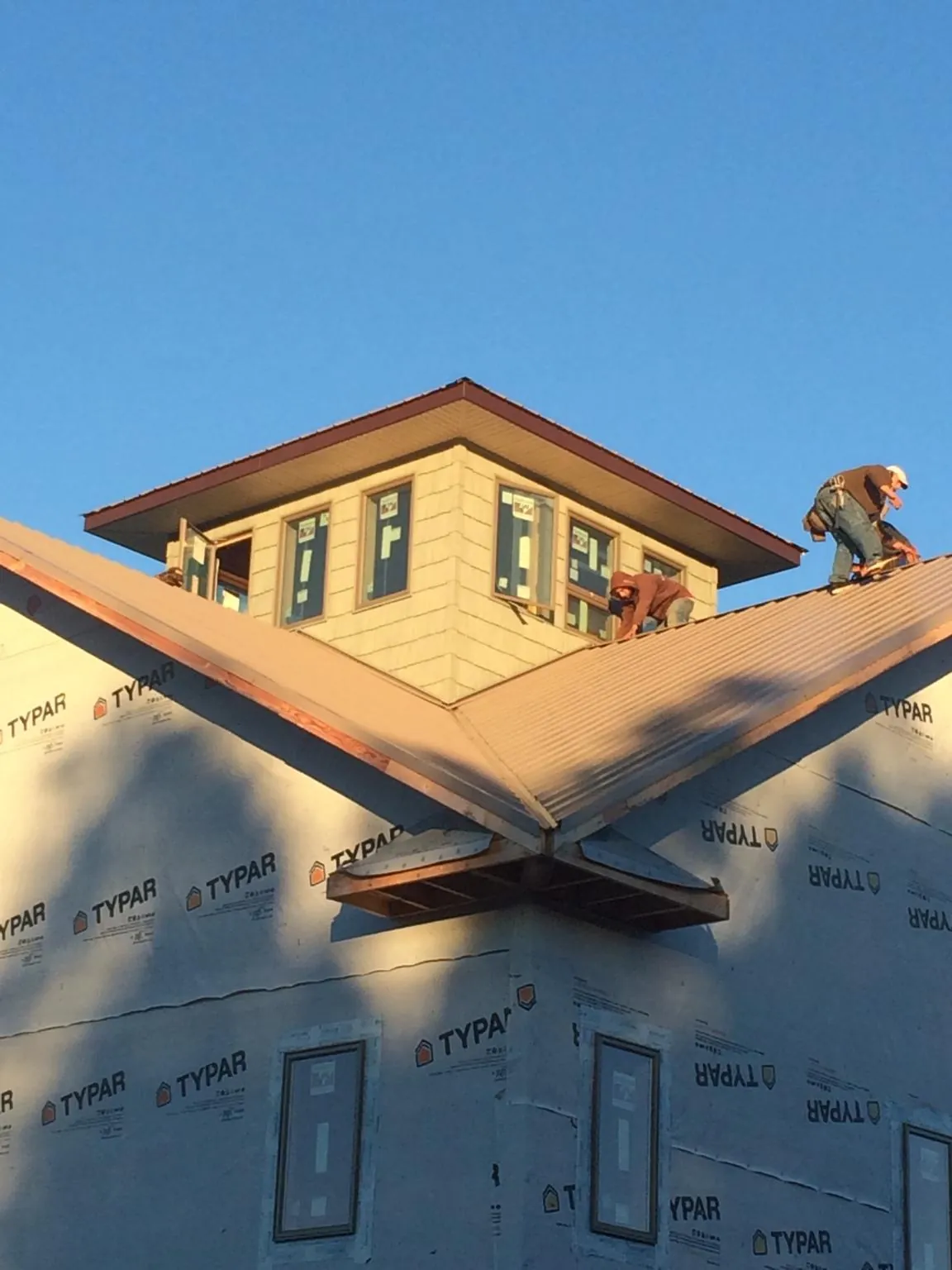 Roofers working around a rooftop cupola on a new metal roof at sunset — Roof Waterproofing in Mickleton by Roofing Brothers